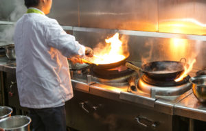 Crowded kitchen, a narrow aisle, working chef.